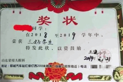 一张落款为王集小学的小学生奖状上，印上了“山东梁堤头眼科”的广告。新京报我们视频截图